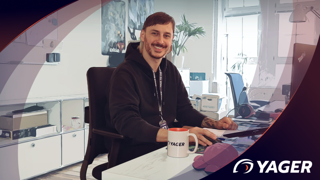 Person sitting at desk smiling with YAGER cup in front of him